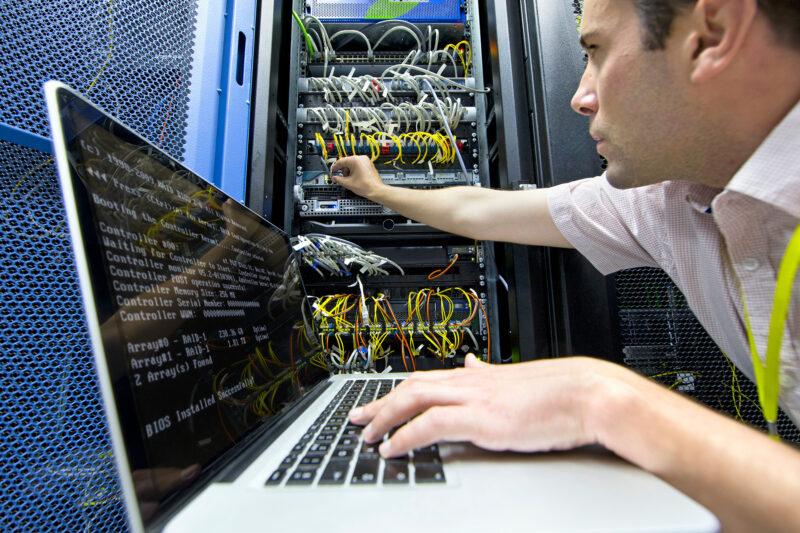 Technician with laptop in server data centre